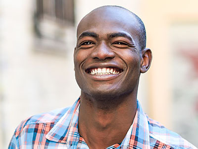 The image shows a man with a broad smile, looking directly at the camera.