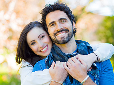 A young man and woman hugging each other with smiles on their faces.