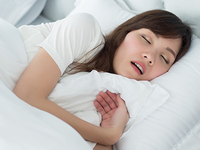 A woman lying in bed with her eyes closed, suggesting she is asleep.